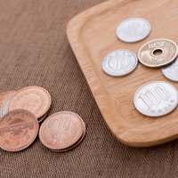 木製トレイと布の上に並ぶ日本の硬貨の写真