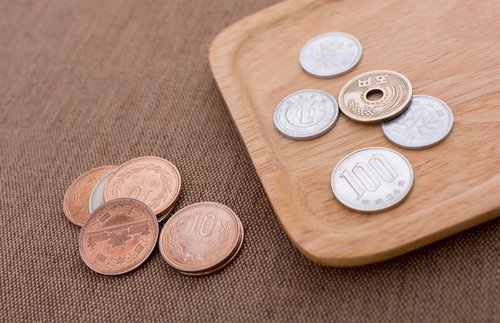 木製トレイと布の上に並ぶ日本の硬貨