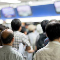 場外馬券場のモニターを見つめる人々の写真