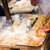 屋台に並ぶエビフライや揚げ物の串の写真