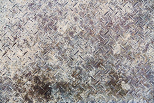 斜め模様の凸凹に錆や汚れが付いた鉄の床板のテクスチャー