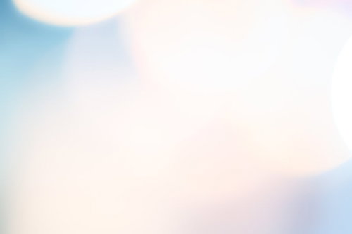 淡い青やピンクが混じった柔らかいぼけた光の円の抽象写真