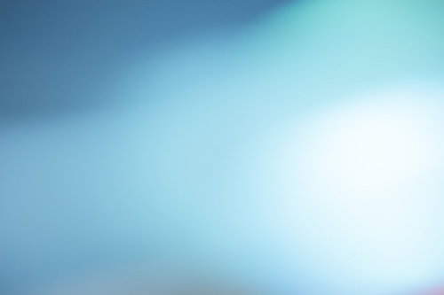中央から右上に光が広がる青系グラデーションのぼけた抽象写真