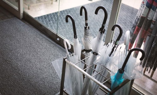 建物の入口に置かれた傘立てとビニール傘