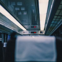 蛍光灯と表示機器がある青みがかった特急電車の車内座席の写真