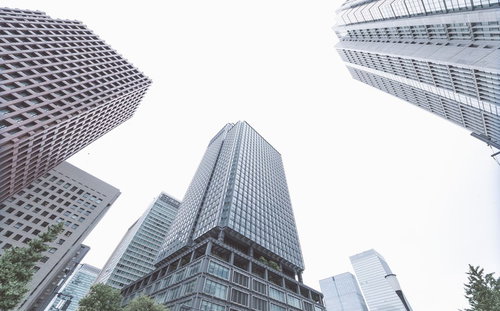 曇り空の下で見上げたガラス張りの高層ビル群