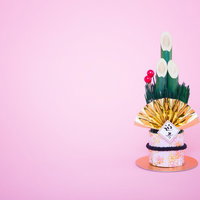 金色の扇と赤い梅の花が付いたピンク台座の迎春の門松飾りの写真