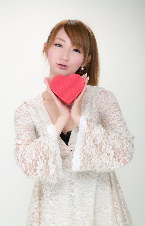 赤いハート型の箱を両手に持つレース服の女性