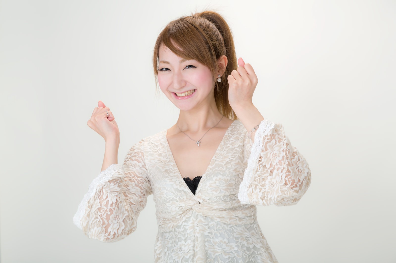 両こぶしを握り上げて応援する笑顔の女性［モデル：to-ko］