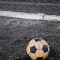 金網フェンスの前に置かれた古いサッカーボールの写真