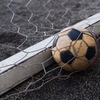 ゴールネットの中の使い古されたサッカーボールの写真