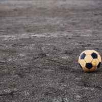 コンクリートの地面に置かれた古いサッカーボールの写真