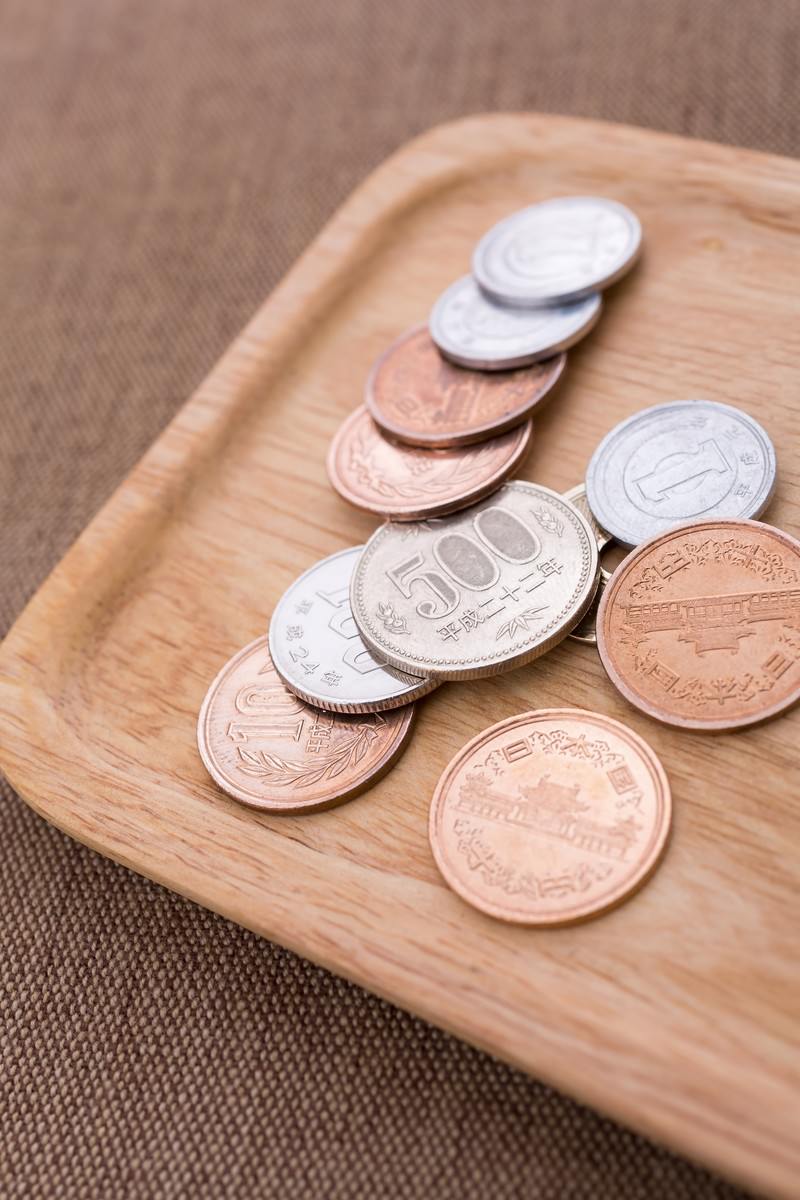 木製トレーの上に500円玉や銅色の硬貨が複数並んでいる