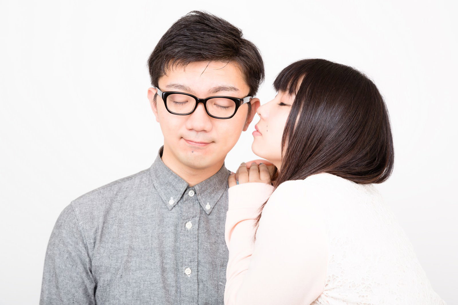 彼氏の耳元に顔を近づける長い髪の彼女［モデル：OZPA Lala］