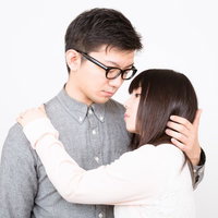 向かい合って抱き合う眼鏡の彼氏と黒髪の彼女の写真