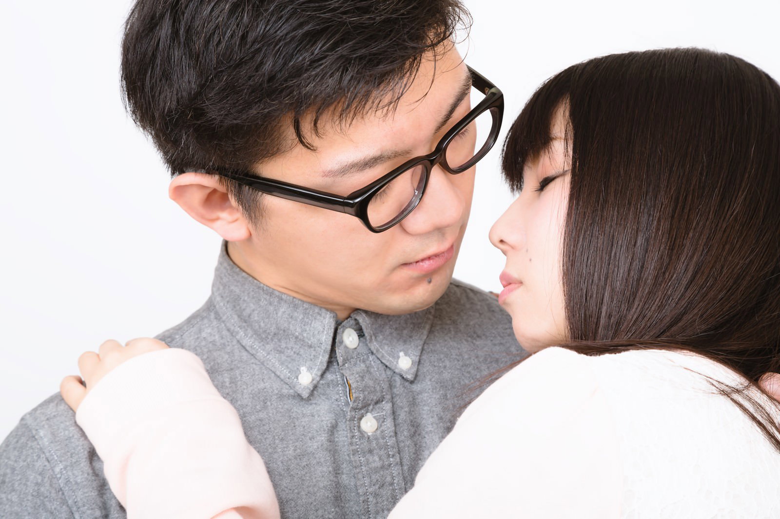 近い距離で見つめ合う眼鏡の男性と黒髪の女性［モデル：OZPA Lala］