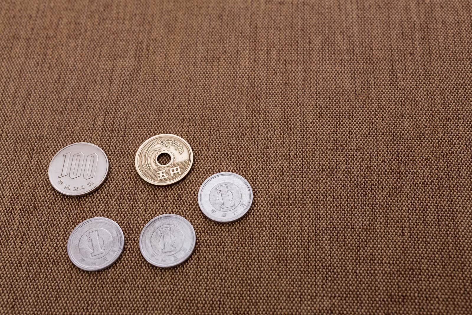 茶色い布地の上に散らばった100円玉と1円玉の硬貨
