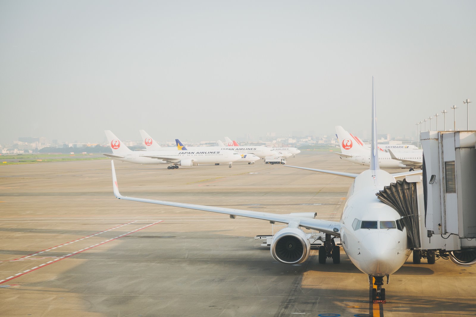 空港のターミナルに接続された白い旅客機と駐機する複数の航空機