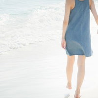 彼氏と彼女が波打ち際で手をつなぐワンピース姿の写真