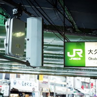 JR大久保駅前の駅名表示板と電気設備の夜間風景の写真