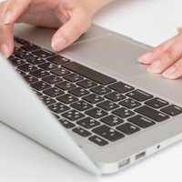 銀色のノートパソコンでタイピングする両手の写真