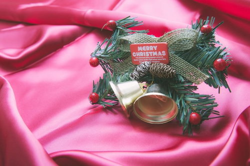 松ぼっくりやベルと赤いタグが付いた緑のクリスマスリース