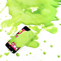 緑の塗料が飛び散るスマートフォンとペンキの創意的な表現の写真