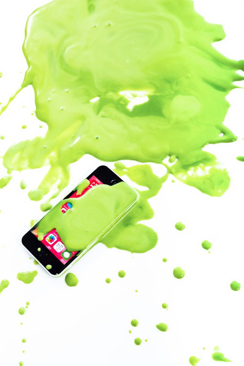 緑の塗料が飛び散るスマートフォンとペンキの創意的な表現の写真
