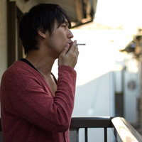ベランダでタバコを吸うお父さんの写真