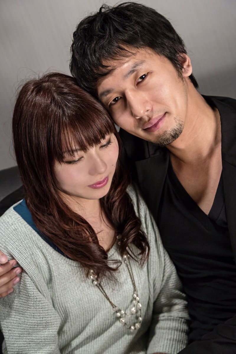 黒いシャツの男性が薄緑グレーのセーターの女性を後ろから抱きしめ、ドヤ顔で微笑む［モデル：大川竜弥 Lala］