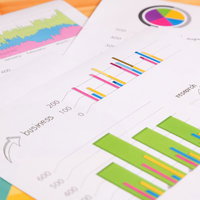 木のテーブルに広げたカラフルなグラフ資料の写真