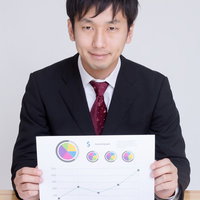 グラフ資料を持って提案するスーツの男性の写真