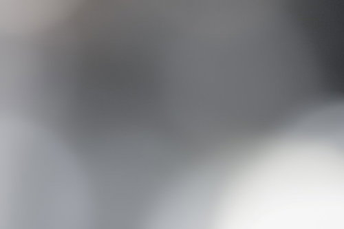 ノイズが混ざったグレイの光のボケ