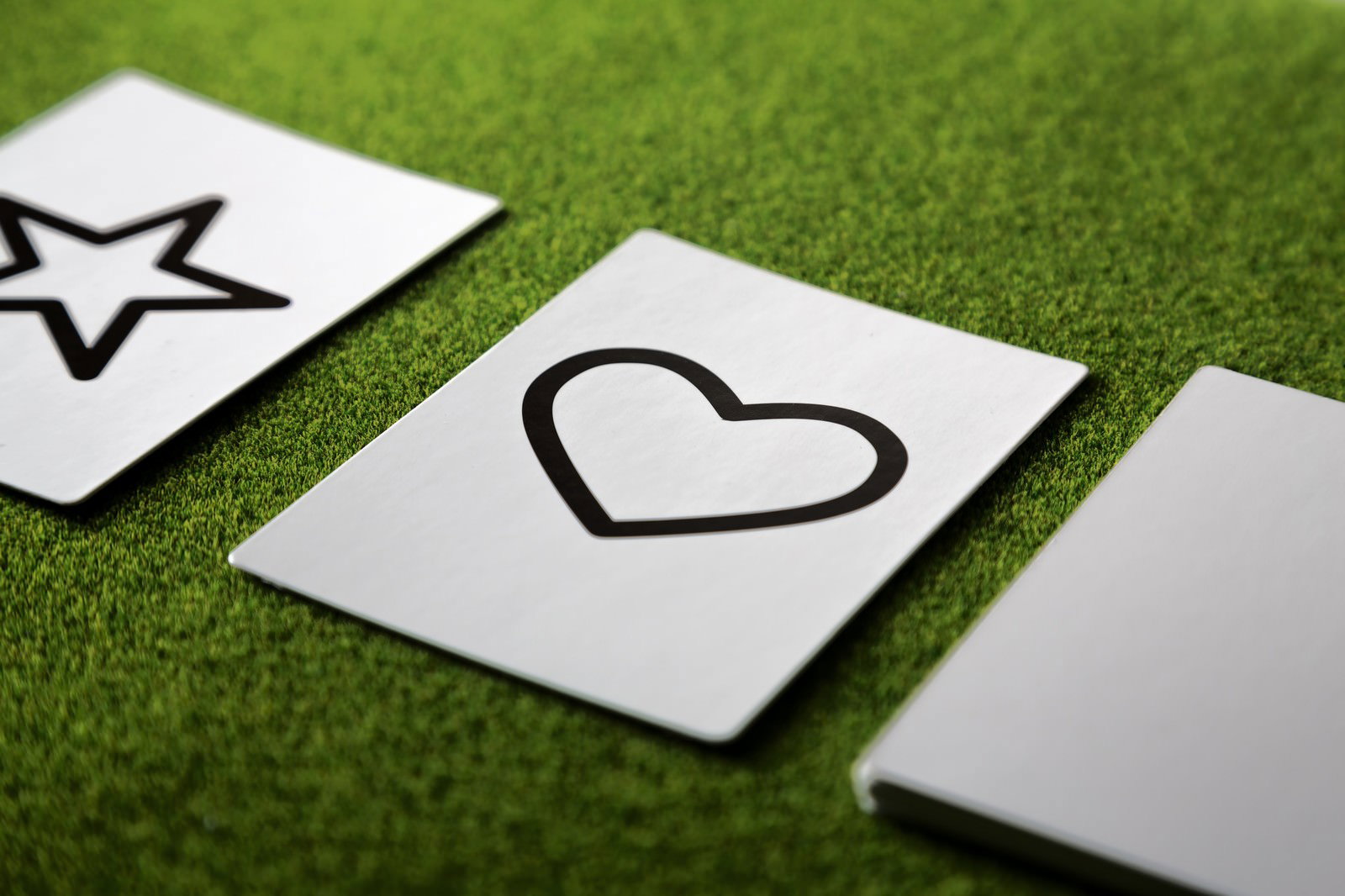 緑の布地の上に白いハートと星のシンボルカードが3枚並べて置かれている