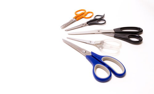 白背景に並べた5本のカラフルなハサミ