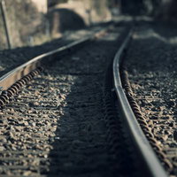 トンネルに向かって曲線を描く2本の線路の写真