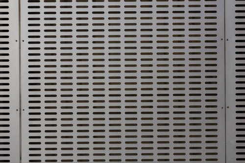 規則正しく穴が開いたグレーのメタルパネル