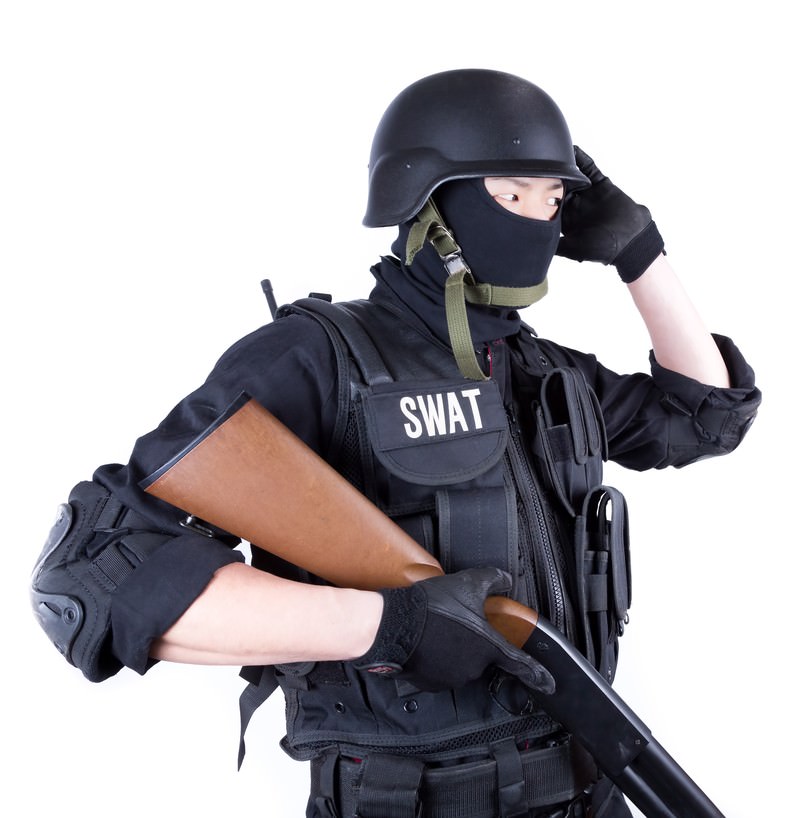 SWATの防弾チョッキを着て銃を持つ黒装備の隊員［モデル：モデルリリース］