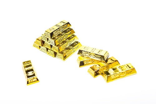 ピラミッド状に積み上げた金色の金塊と延べ棒