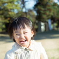 屋外の公園で笑顔のブラウスの短い髪の幼い子供の写真