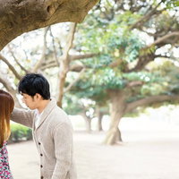 公園の大木に寄りかかるカップルの写真