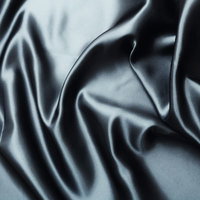 光が当たり折り目やしわが重なる光沢のある黒いサテン生地のテクスチャーの写真