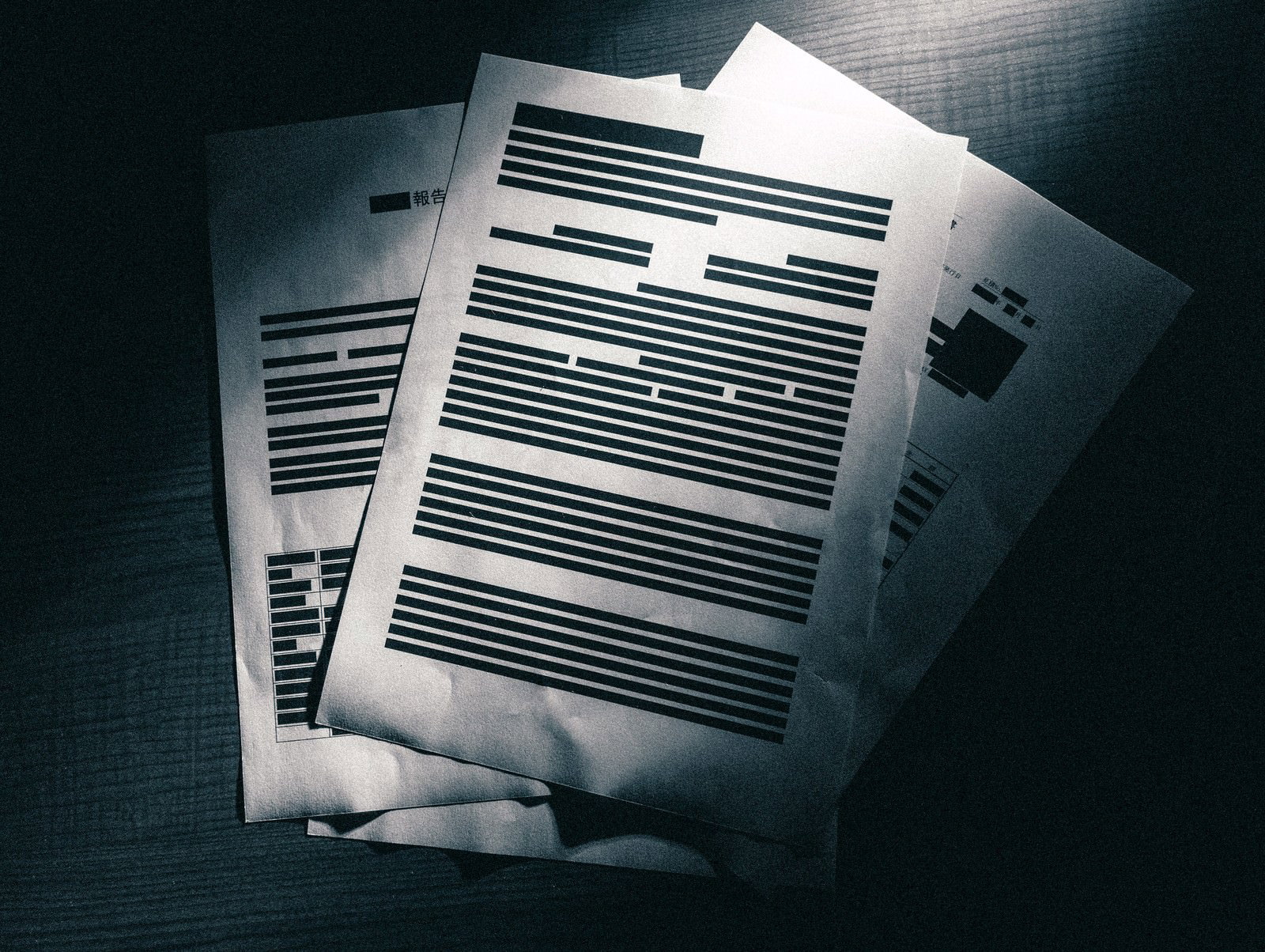 机の上に重ねられた黒塗りされた機密書類