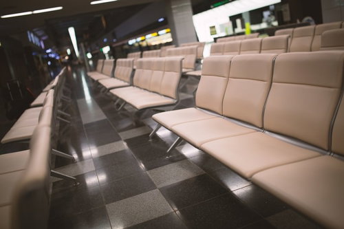 金属フレームのベージュの長椅子が並ぶ空港の待合室
