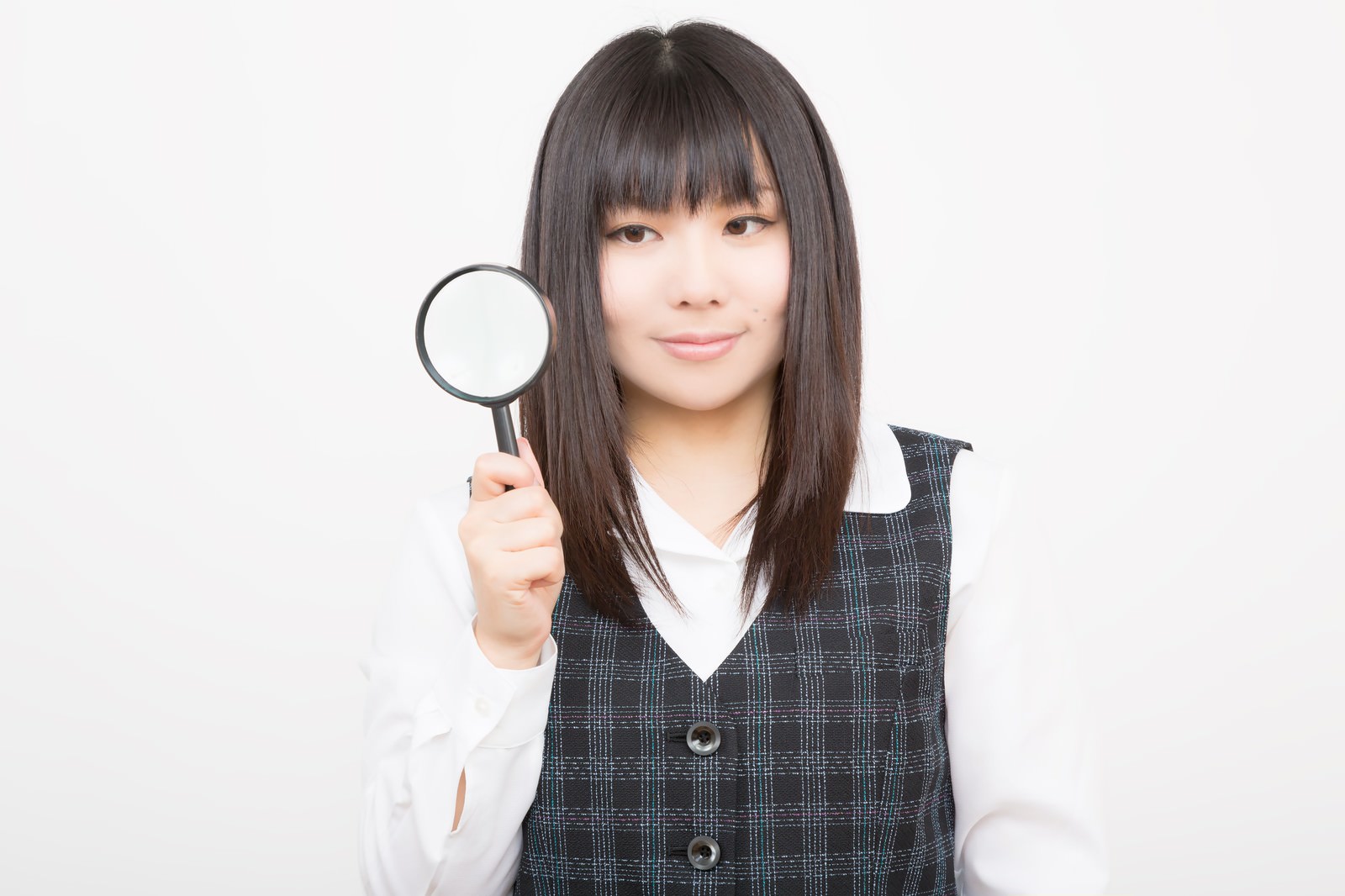 Woman in plaid vest holding magnifying glass indoors