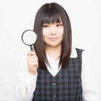 虫眼鏡を持つチェック柄ベストの女性の写真