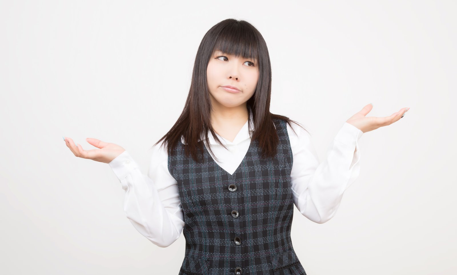 チェック柄ベストの女性が両手のひらを上に向けて広げて困惑している［モデル：Lala］