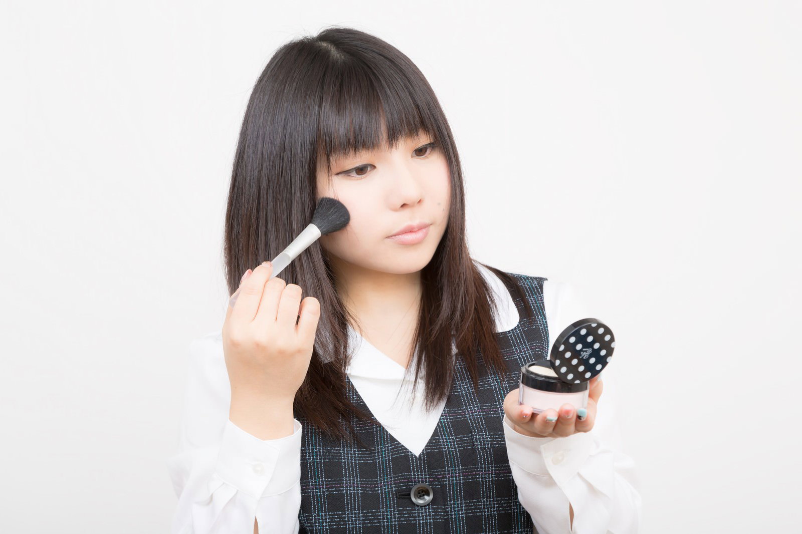 化粧ブラシとパウダーケースを持つチェック柄ベストのOL［モデル：Lala］