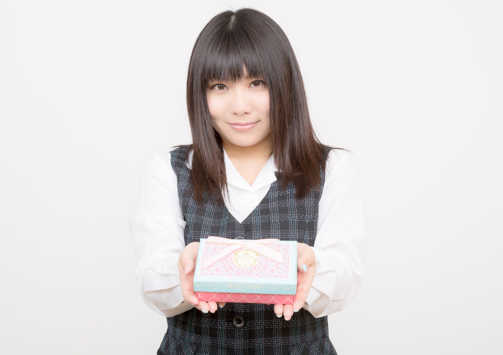 箱を両手で持つチェック柄ベストのOL［モデル：Lala］