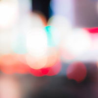 夜の暗い空間にぼけた光の粒や線が浮かぶピンぼけの繁華街写真の写真